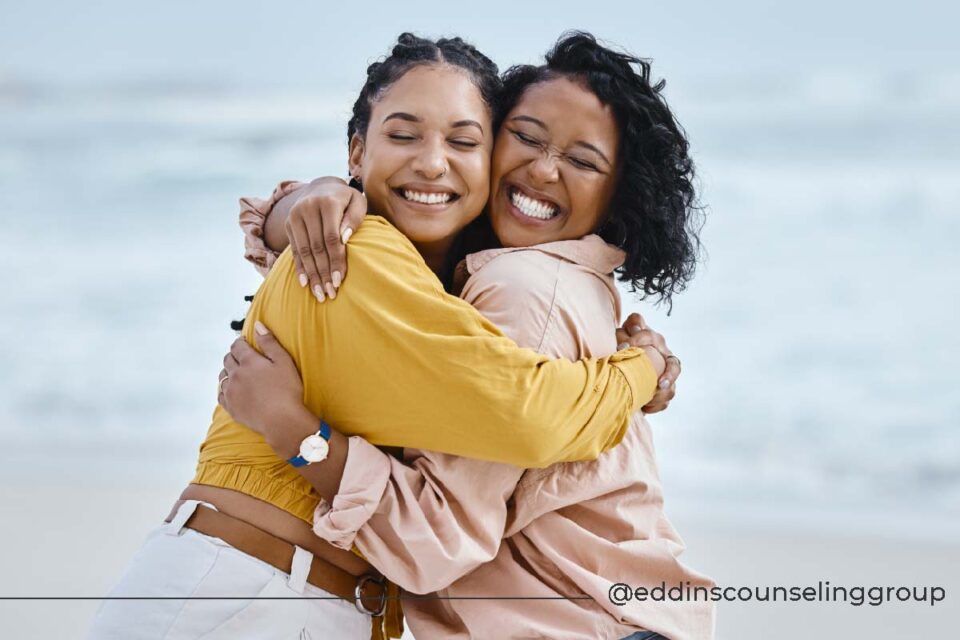 lesbian couple hugging by beach 