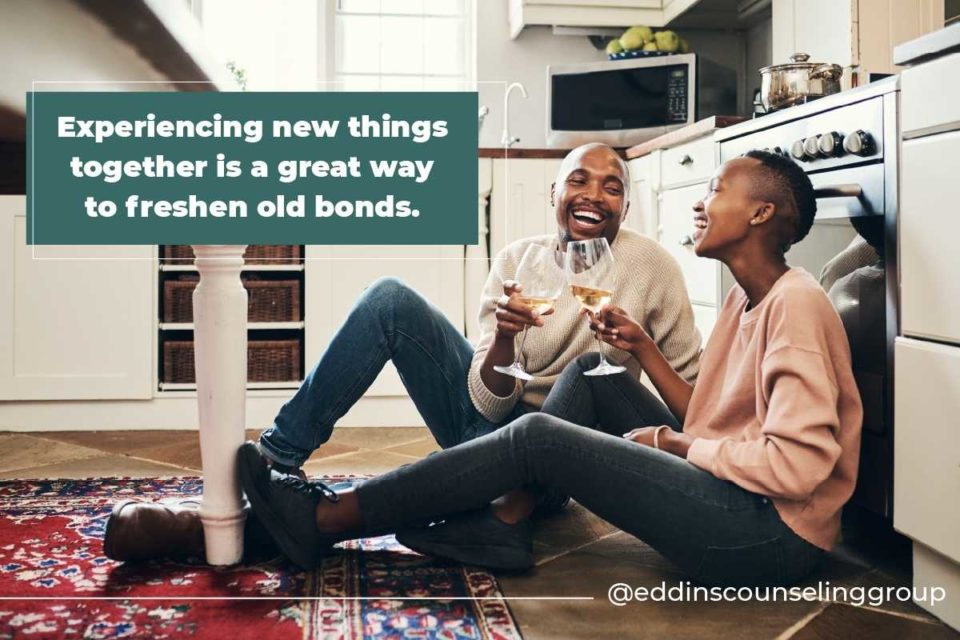 smiling laughing black couple sitting on kitchen floor drinking wine together how to reconnect with your partner