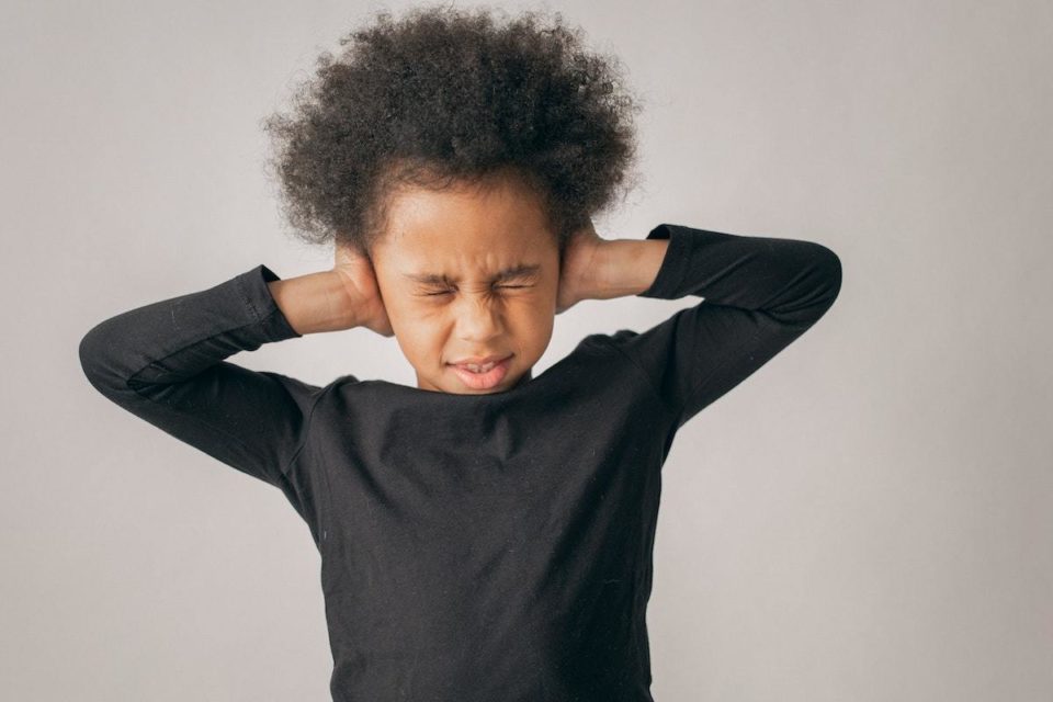 Child with anxiety covering ears