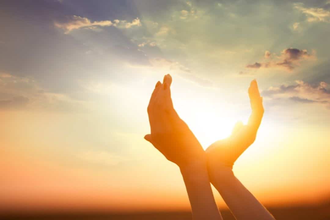 hands holding sun at dawn