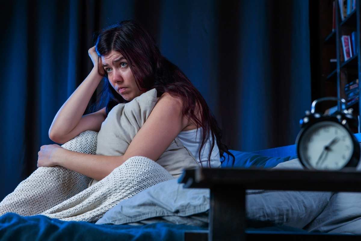 A woman sitting in her bed at night because she can't sleep