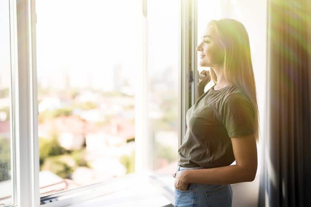 Seasonal Affective Disorder 15 strategies to help you cope white woman standing by window smiling