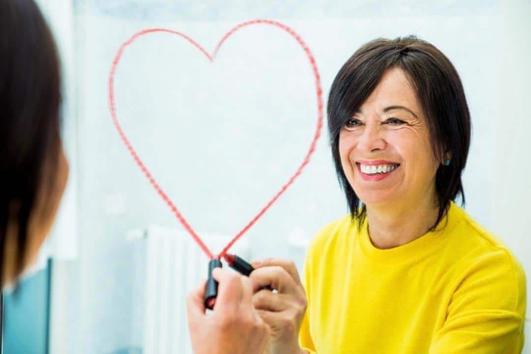 Self-Compassion is a Life Skill: 6 Self-loving Ways to Make Life More Manageable white woman drawing lipstick heart on mirror