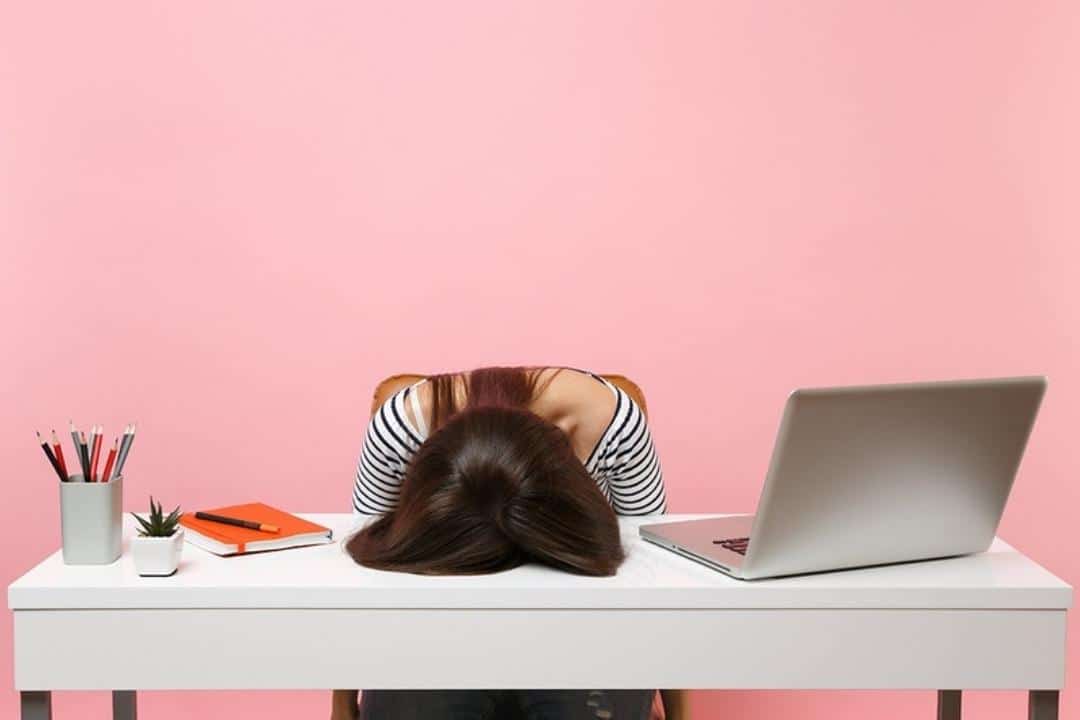 The Mind-Gut connection white woman slouched over desk at work