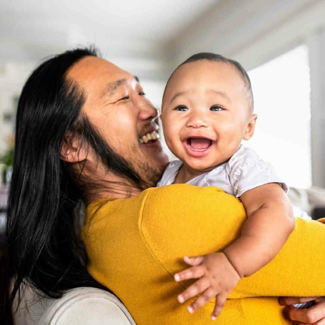 father holding happy baby over shoulder resilient parenting support group