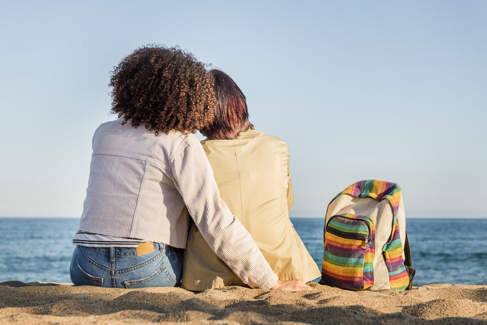 Image of an interracial couple sitting next to each other at the beach. Finding a LGBTQ therapist in Texas is important when exploring sexuality. We can help you find "LGBTQ+ counseling near me" in Houston, TX and Sugar Land, TX. Both individually and LGBT+ relationship counseling. Call today to get started 