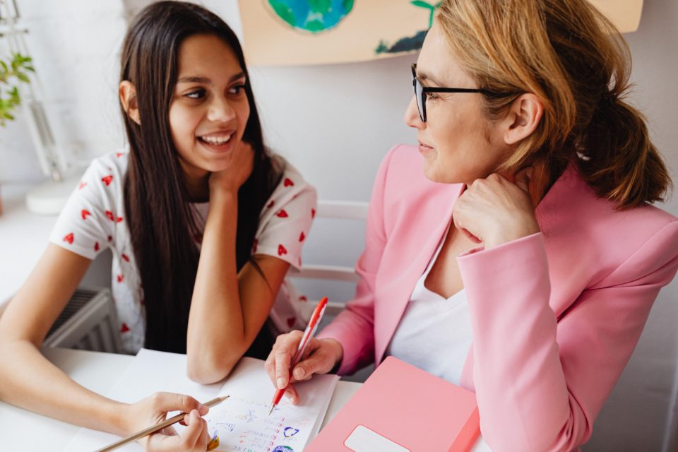 parent and daughter sit at a desk working on an assignment