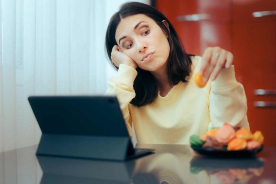 woman procrastinating work by overeating snacks