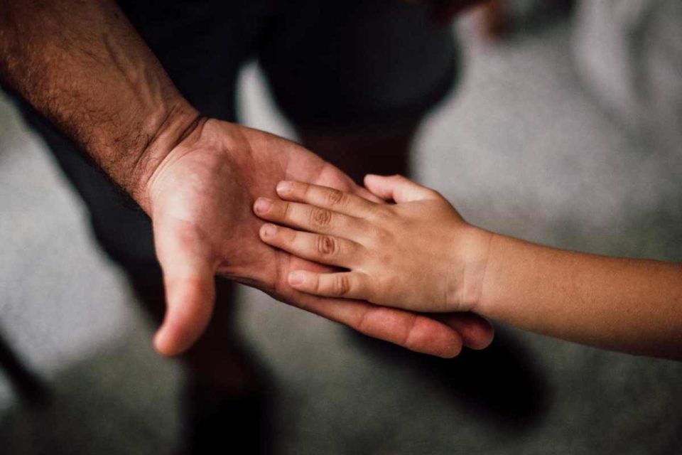 raising a child on the spectrum image of autistic child's hand in parent's hand
