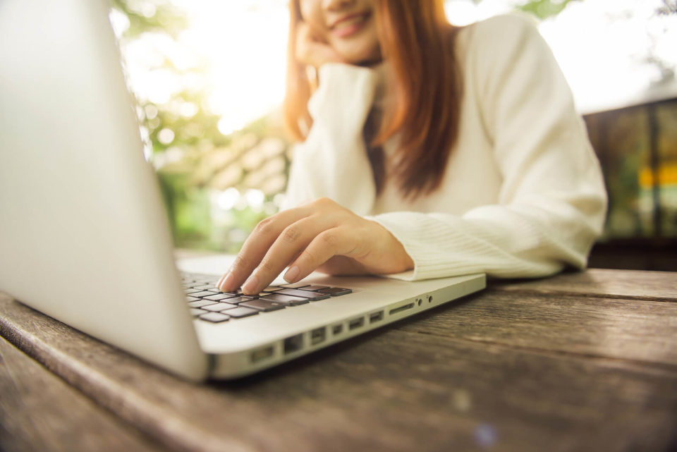 Image of a woman smiling while typing on a laptop. talking with an online therapist in Texas. Not having to commute is just one of the greatest parts of teletherapy in Texas. You can receive specialized care even if you are not physically located near the practice with online counseling. Are you ready to start online therapy in Texas? If so call today!